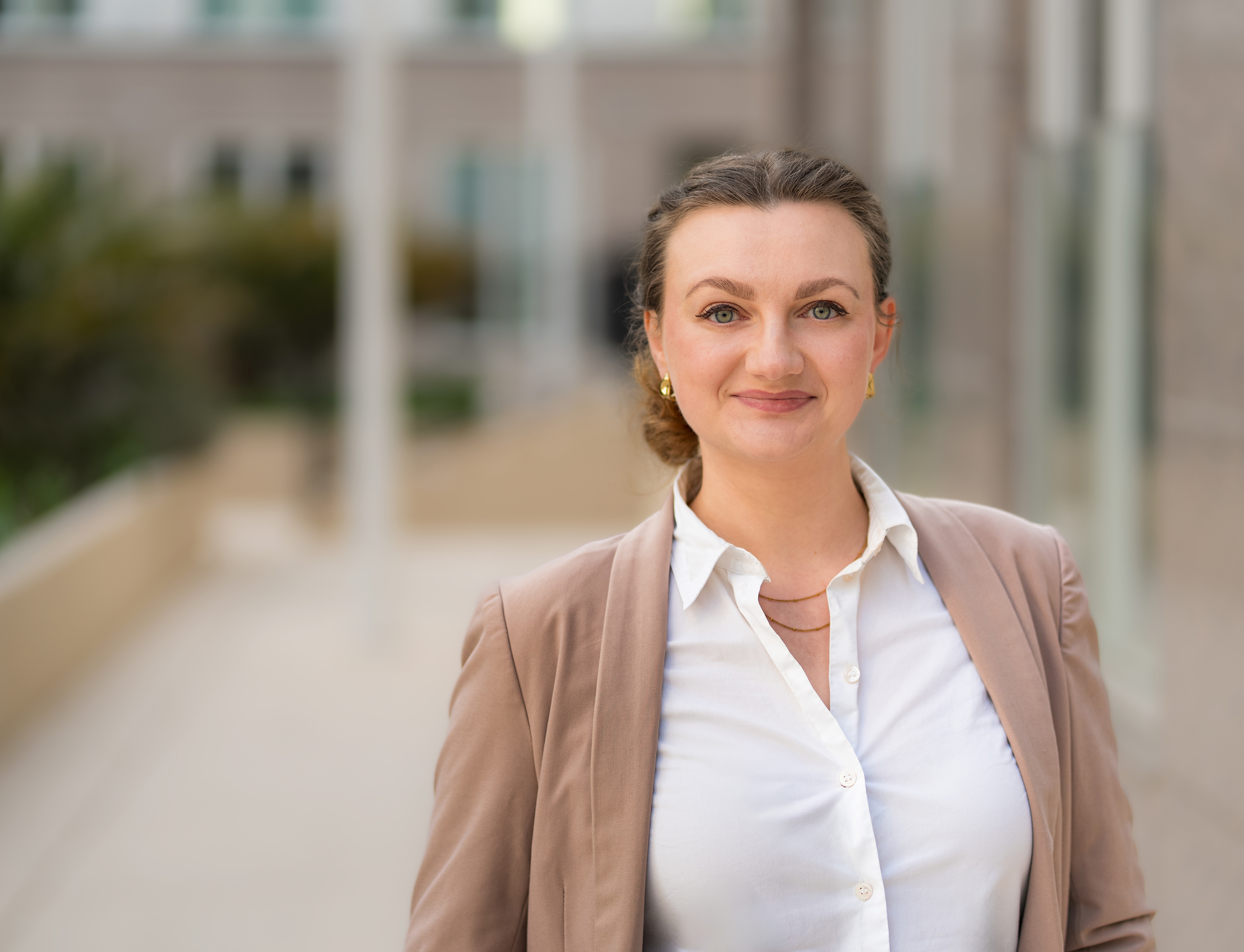 Businessportrait einer Frau im Blazer vor moderner Bürofassade
