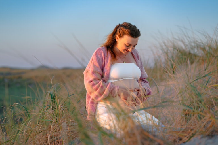 Schwangere Frau in den Dünen bei Sonnenuntergang – Babybauch-Shooting
